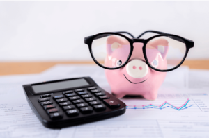 piggy bank wearing glasses next to a calculator