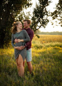 husband hugging wife from behind, hands on pregnant belly