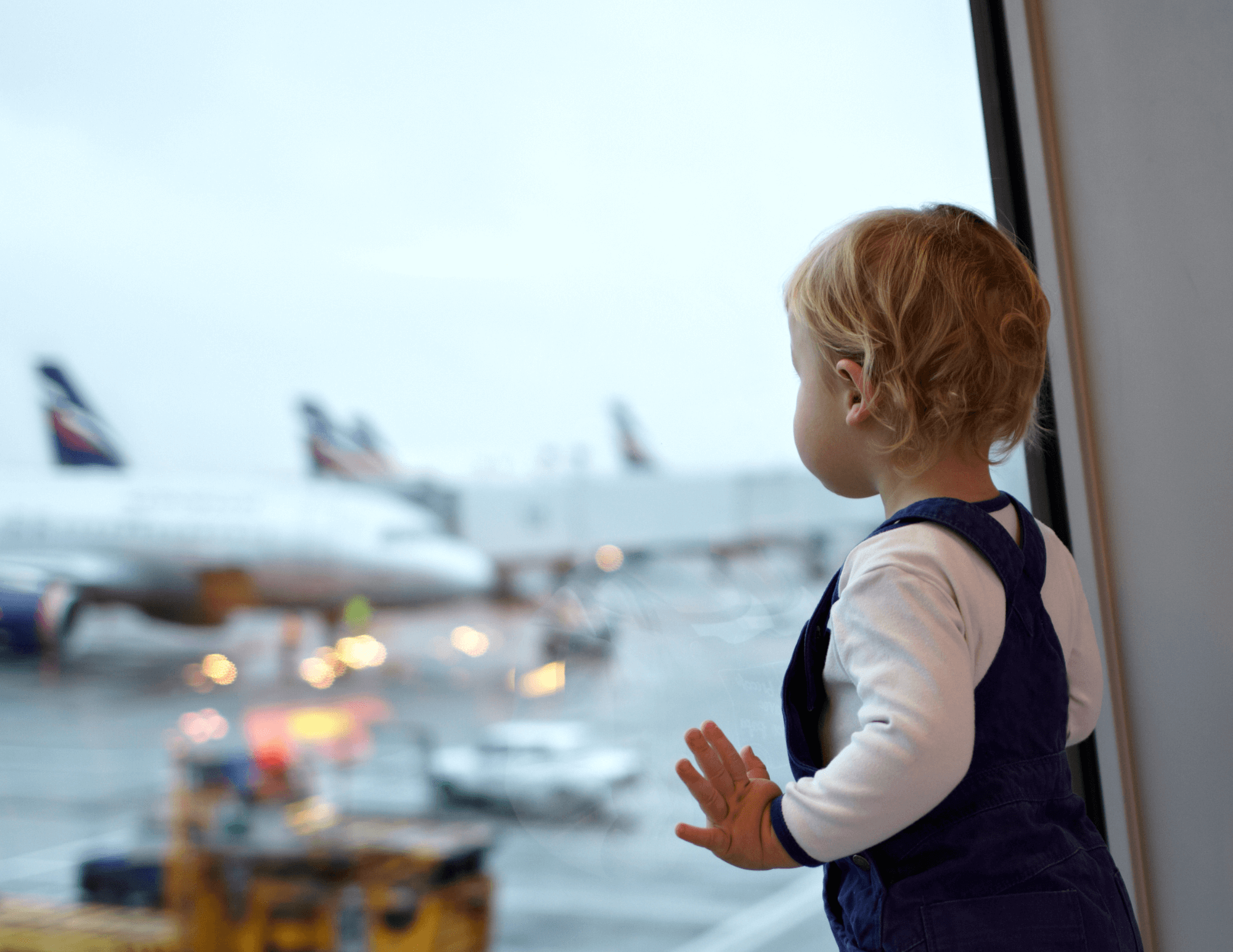 baby looking at plane out airport window